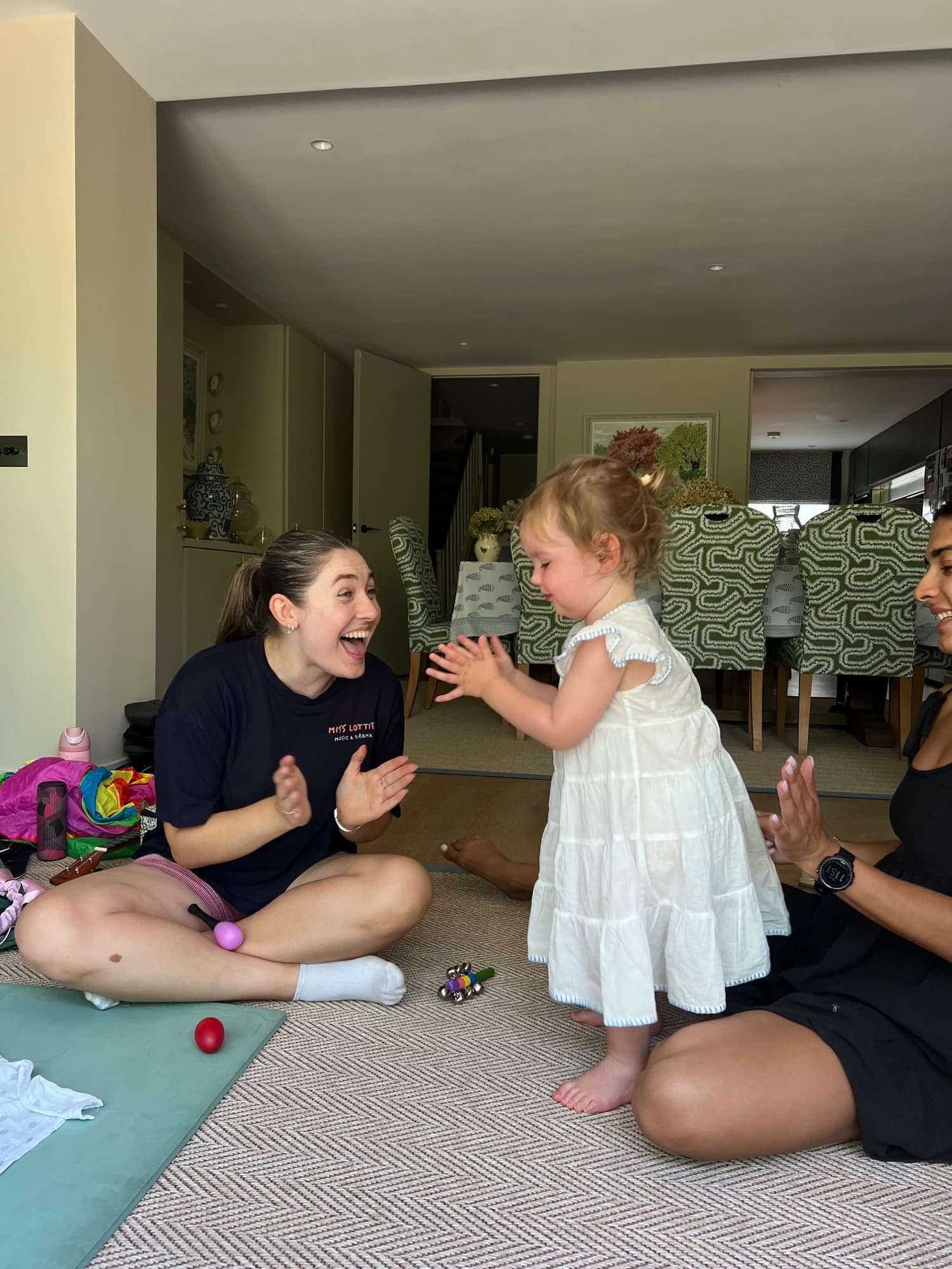 Lottie and a toddler in white clapping and laughing together
