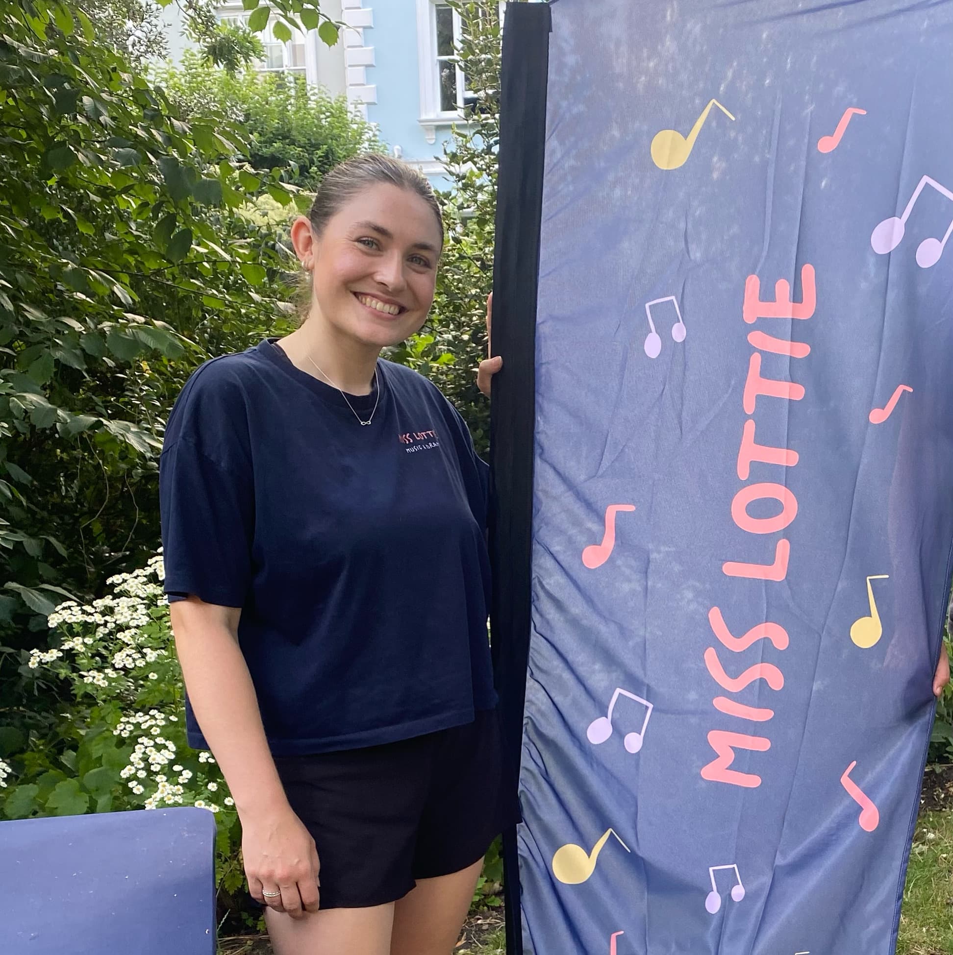 Lottie smiling next to the Miss Lottie banner