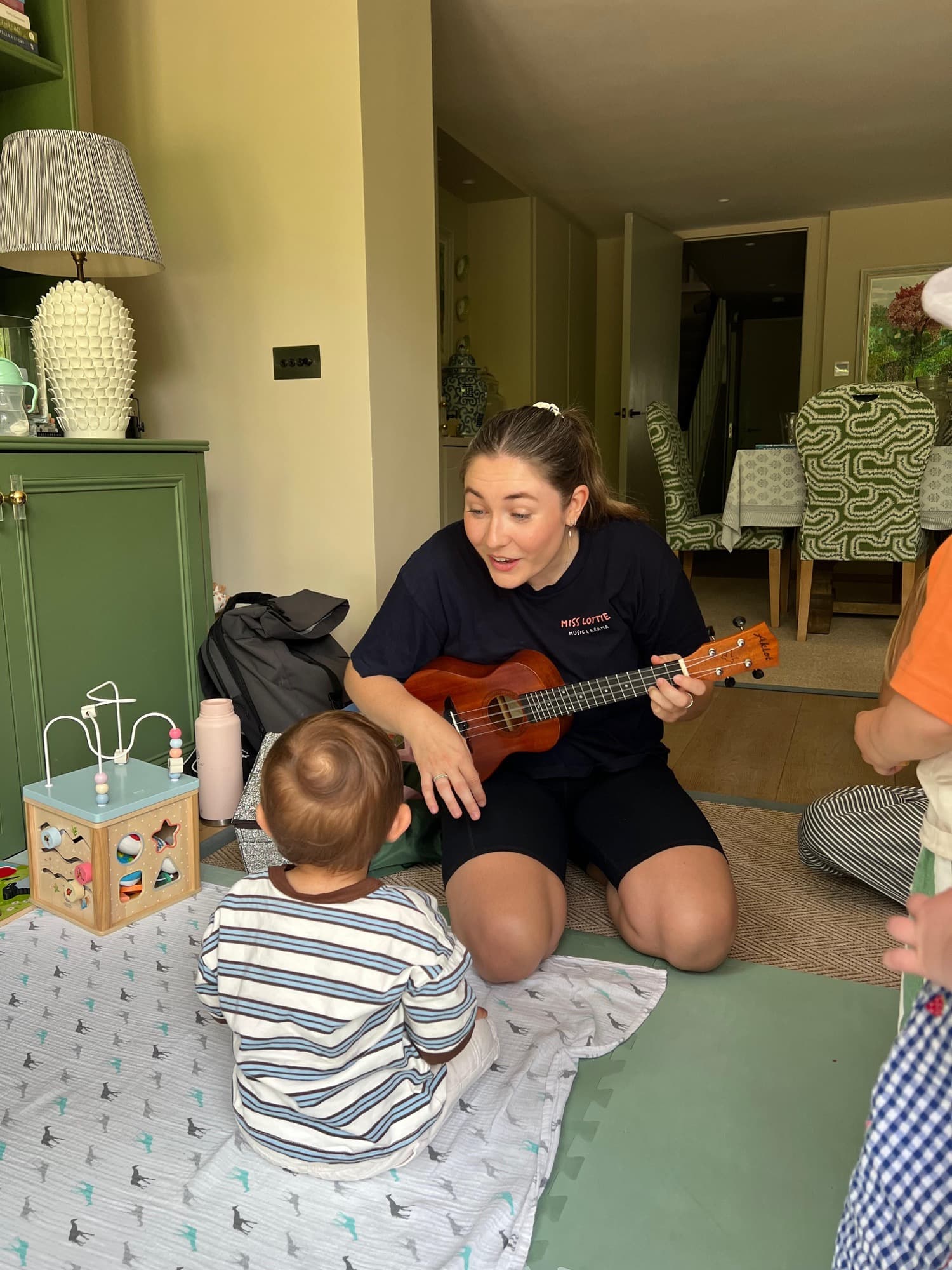 Lottie playing ukulele for a baby on the floor